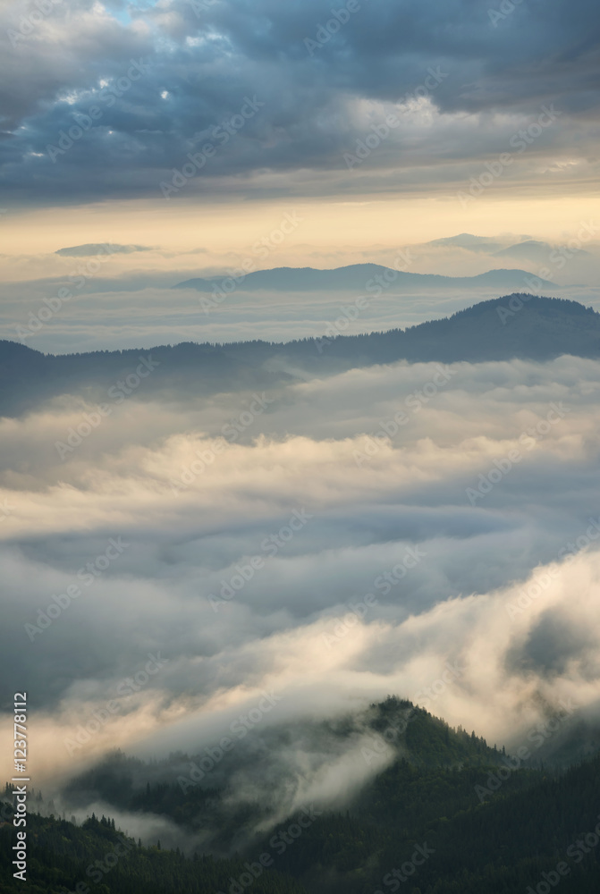 High mountain ridge in the clouds during sunrise. Beautiful panoramic landscape..