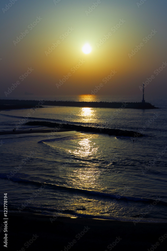 The lighthouse on the pier at sunset in the Mediterranean Sea