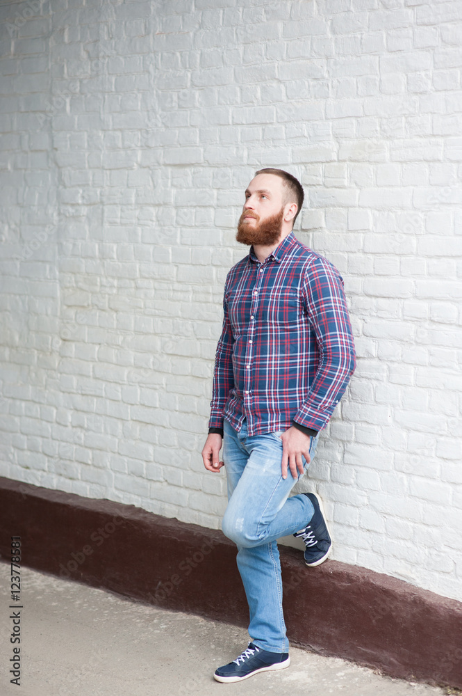 bearded man is leaning on a brick wall bearded man is leaning on a brick wall