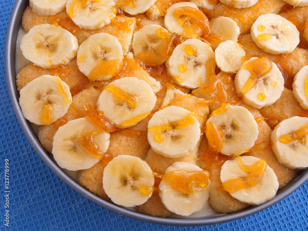 Homemade cake with bananas and caramel in a bowl. Shot on blue b Homemade cake with bananas and caramel in a bowl. Shot on blue b