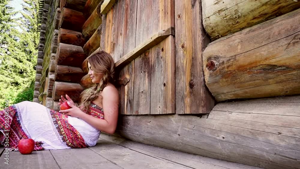 Attractive fashion model sitting on the porch of a wooden house, posing ...