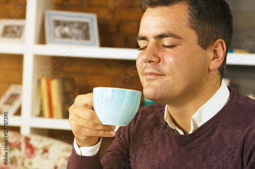 Young man enjoying with closed eyes drink coffee, tea or chocolate.