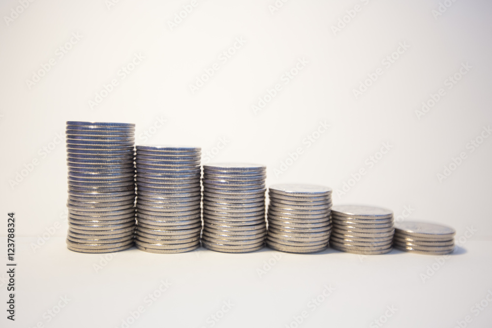 Silver coins stacked on a white background signifying various metaphors for finance and economics Silver coins stacked on a white background signifying various metaphors for finance and economics