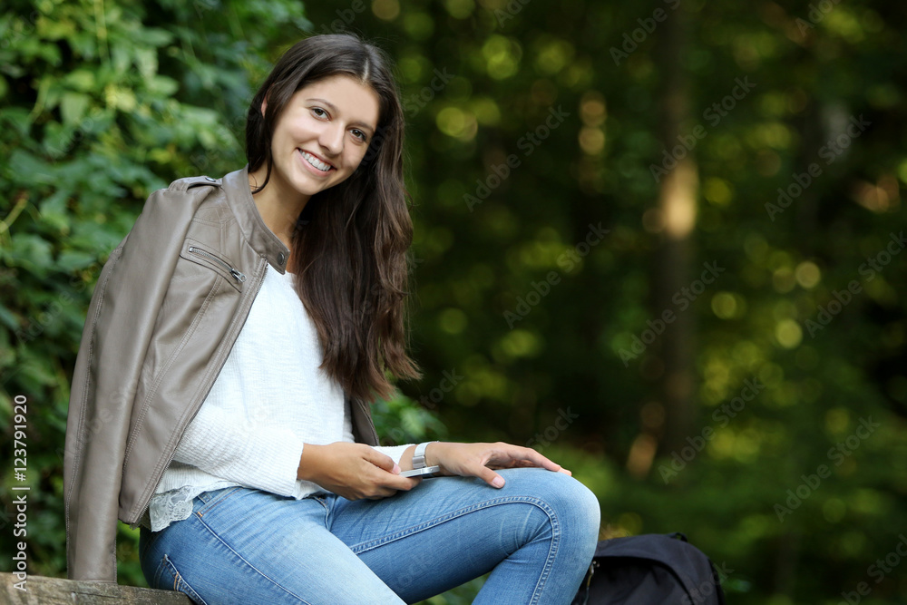 Glückliche junge Frau mit Smartphone im Park Glückliche junge Frau mit Smartphone im Park