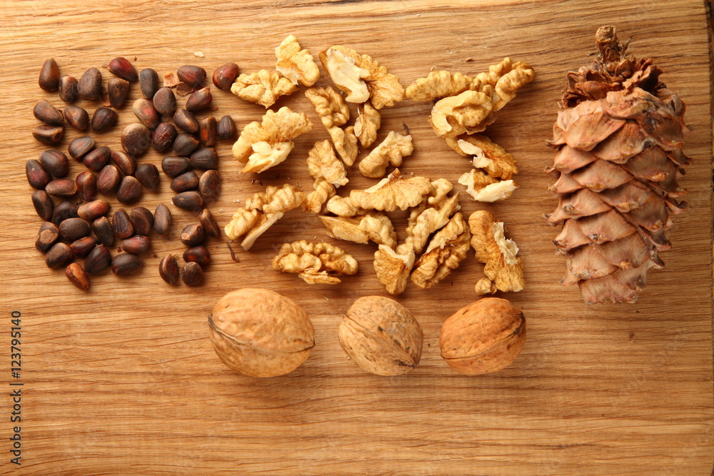 Walnut and pine nuts on a cutting board made of oak/ Walnut and pine nuts on a cutting board made of oak Walnut and pine nuts on a cutting board made of oak/ Walnut and pine nuts on a cutting board made of oak