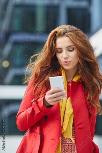 beautiful girl in red coat speaks by phone on the street