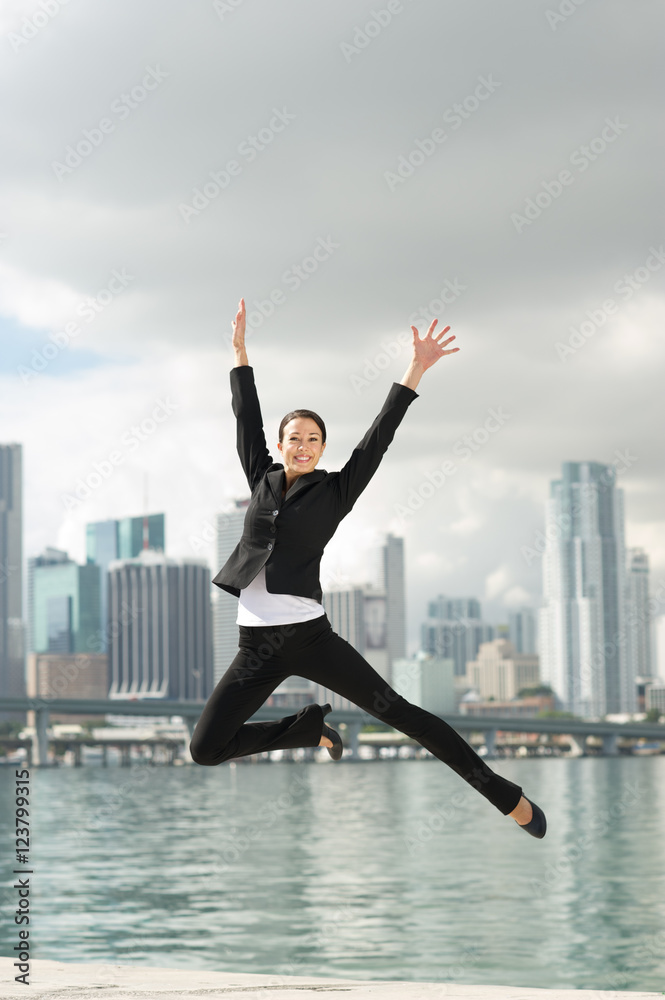 Happy Businesswoman Leaping with Miami Skyline in Background