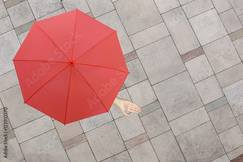 Red umbrella and a hand of man standing on stone floor and hand