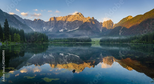 reflection of mountain Mangart in a mountain lake Laghi di Fusine at sunrise, Julian Alps, Italy