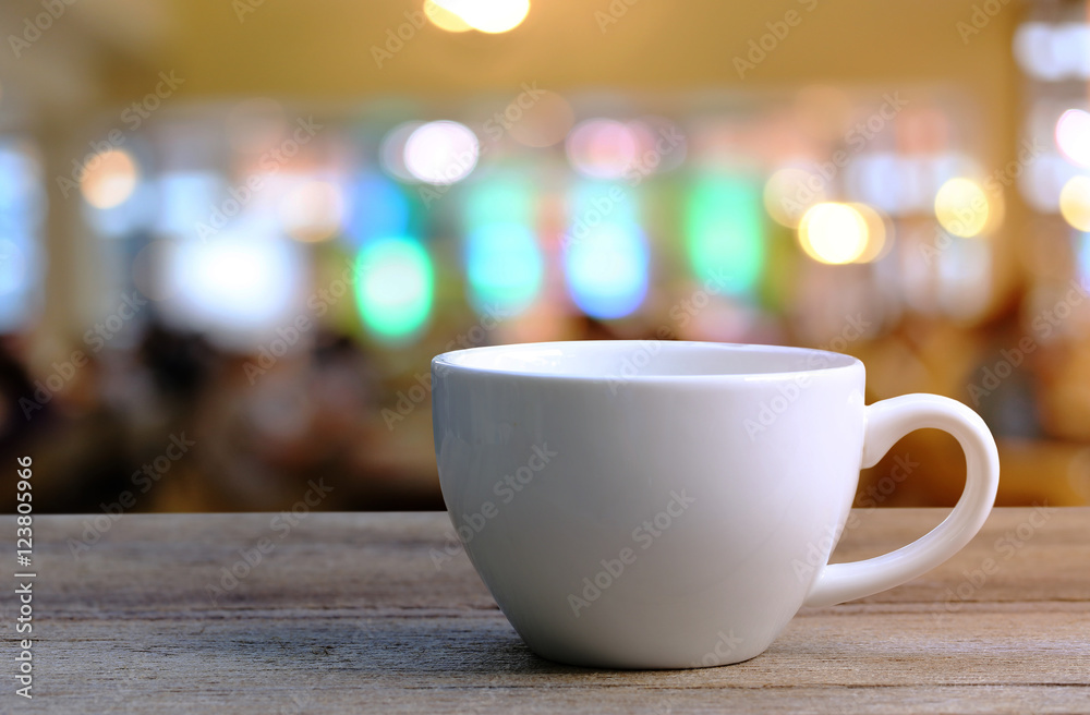 White Coffee cup on wooden table in coffee shop blur background. White Coffee cup on wooden table in coffee shop blur background.