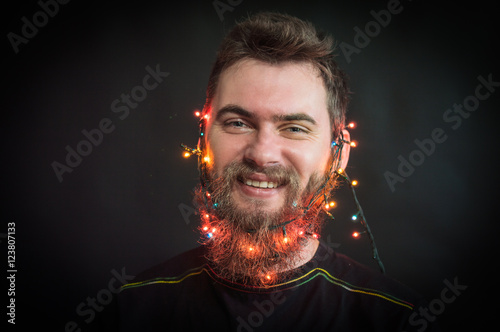 Bearded man smiling. with glowing garland on his head. On a black background. photo