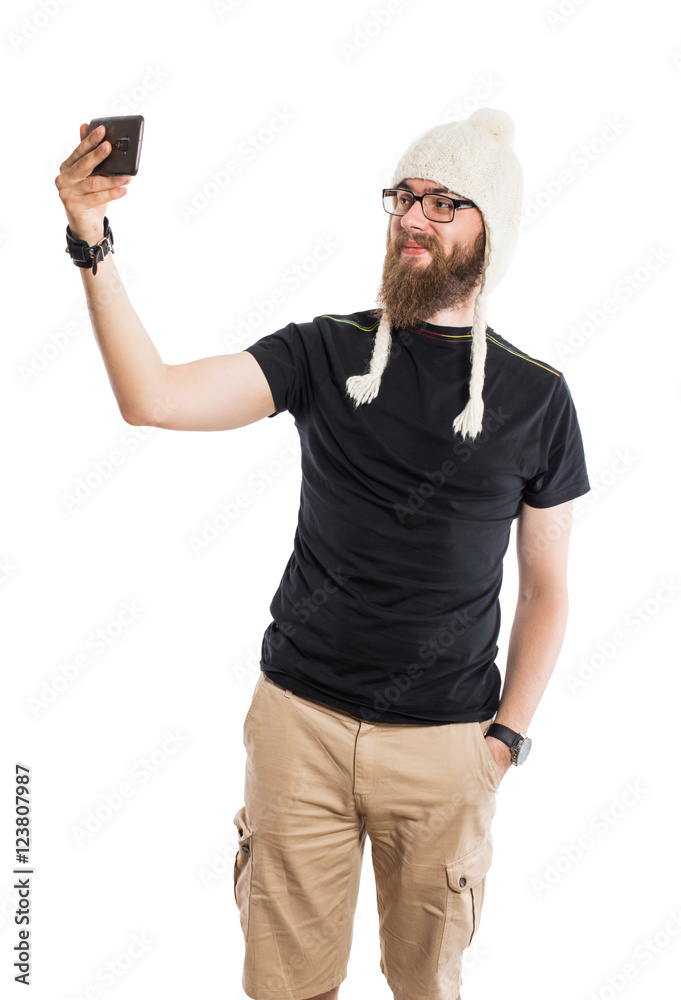 Joyful man with a beard in a funny hat and sunglasses. It makes selfie phone. On white, isolated background. Joyful man with a beard in a funny hat and sunglasses. It makes selfie phone. On white, isolated background.