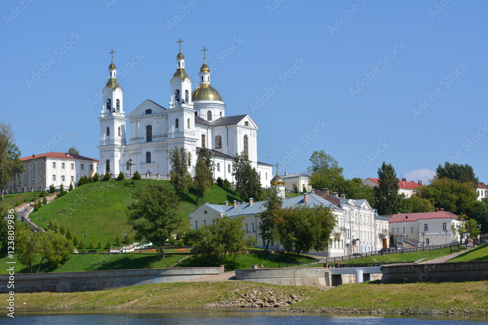 beautiful white cathedral with golden domes of the river on a background of blue sky