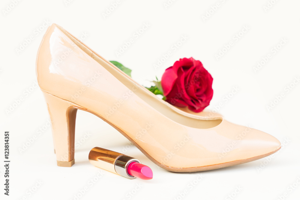 Nude colored high heels still life with red rose flower bud and lipstick Nude colored high heels still life with red rose flower bud and lipstick