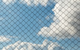Metal mesh netting on the blue sky background and clouds