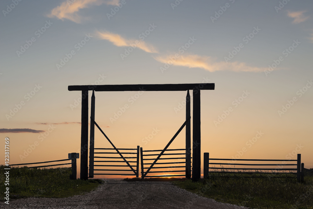 horizontal image of a silhouette of a wooden fence entry gate for the animals under a beautiful sunset.