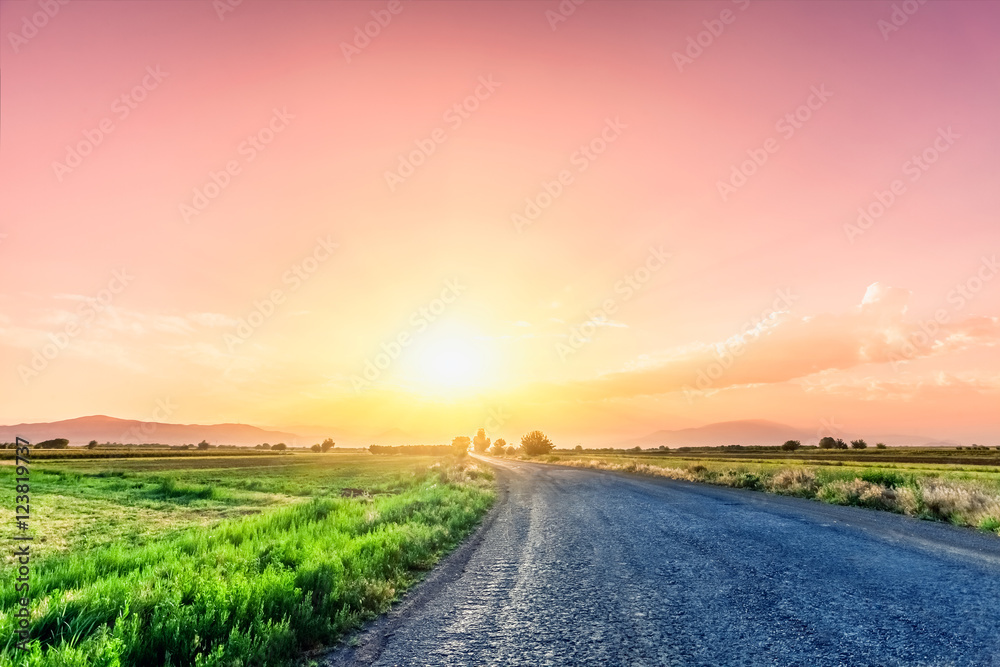 Road on meadow with beautiful sunset sky