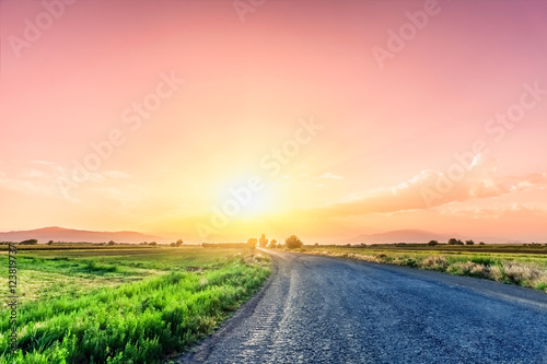 Road on meadow with beautiful sunset sky