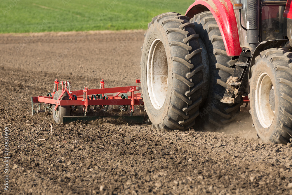 Farmer in tractor preparing land with seedbed cultivator Farmer in tractor preparing land with seedbed cultivator