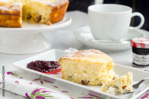 Cottage cheese cake with fruit jam and a cup of coffe on a kitchen table.
