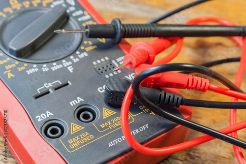 Digital multimeter with the connected probes on a table in a workshop