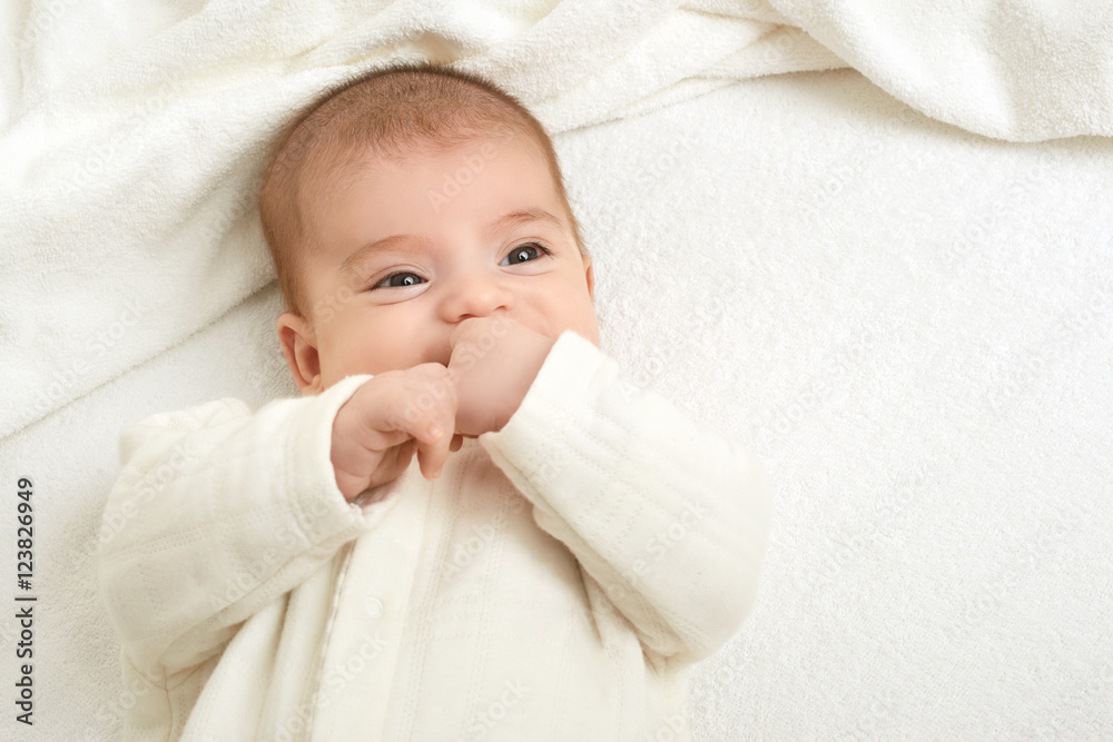 baby portait lie on white towel in bed, yellow toned