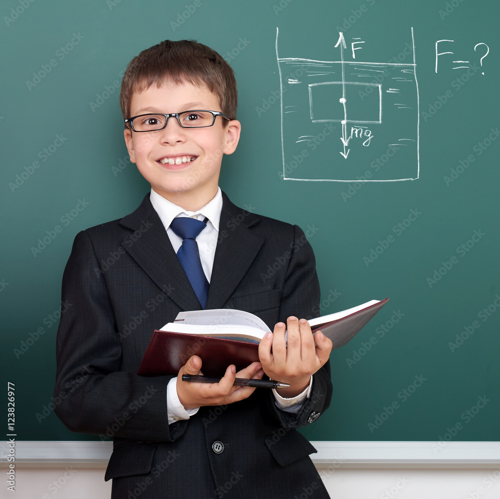 school boy with book, archimedes principle drawing on chalkboard background, dressed in classic black suit, education concept