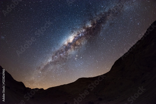 Starry sky and Milky Way arc, with details of its colorful core, outstandingly bright, captured from the Namib desert in Namibia, Africa. The Small Magellanic Cloud on the left hand side.