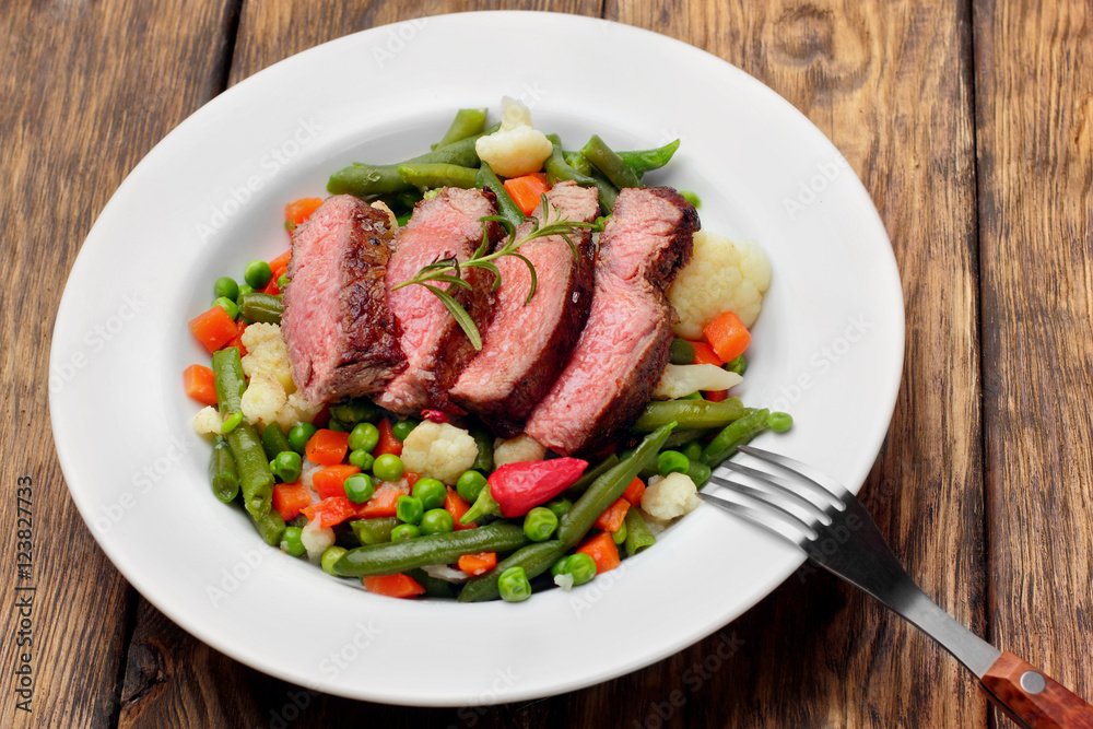 Sliced Beef steak mediu, rare with asparagus beans,cauliflower,carrot and pea on wooden table.closeup selective focus Sliced Beef steak mediu, rare with asparagus beans,cauliflower,carrot and pea on wooden table.closeup selective focus