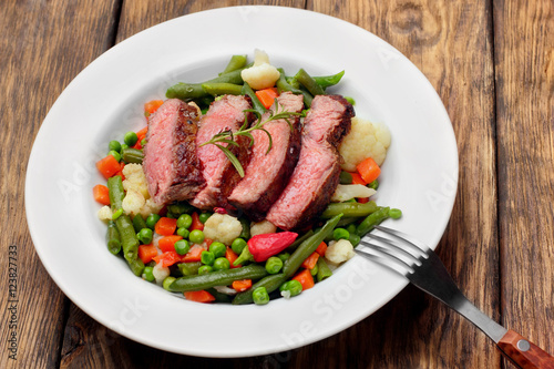 Sliced Beef steak mediu, rare with asparagus beans,cauliflower,carrot and pea on wooden table.closeup selective focus