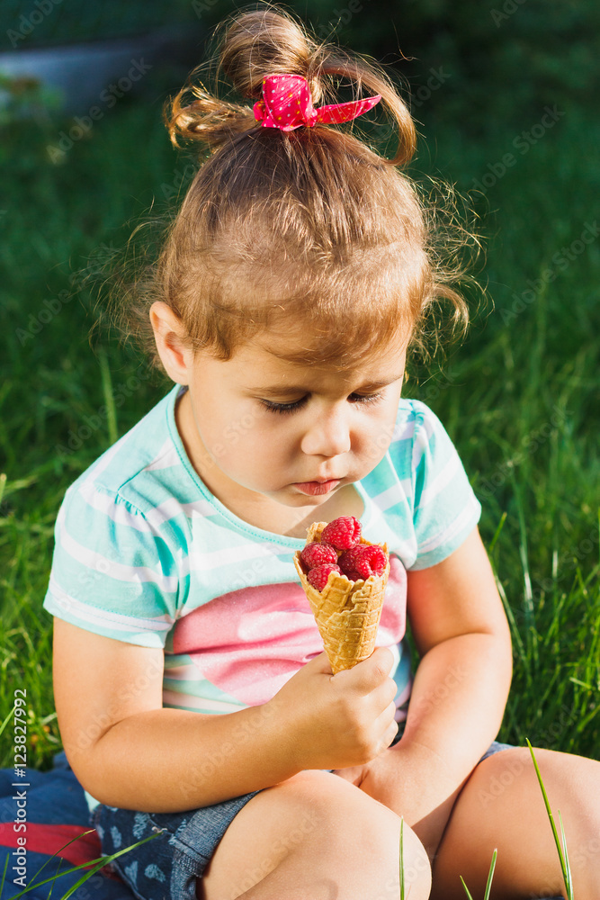 Small girl holds a waffle Cup with raspberry Small girl holds a waffle Cup with raspberry