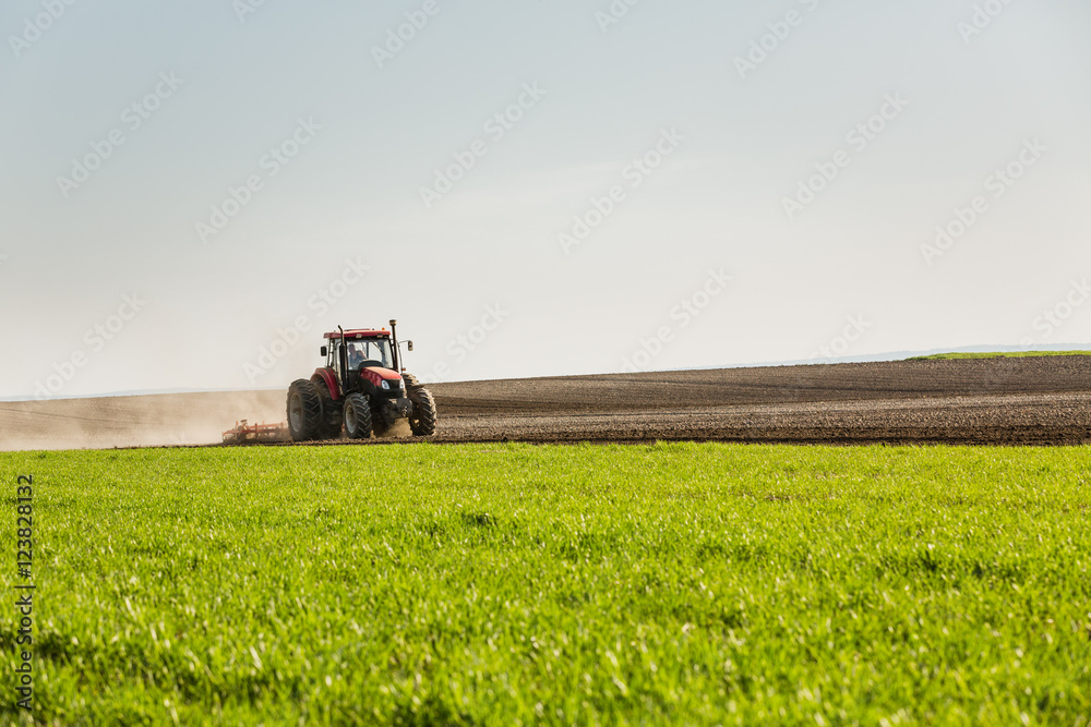 Farmer in tractor preparing land with seedbed cultivator Farmer in tractor preparing land with seedbed cultivator