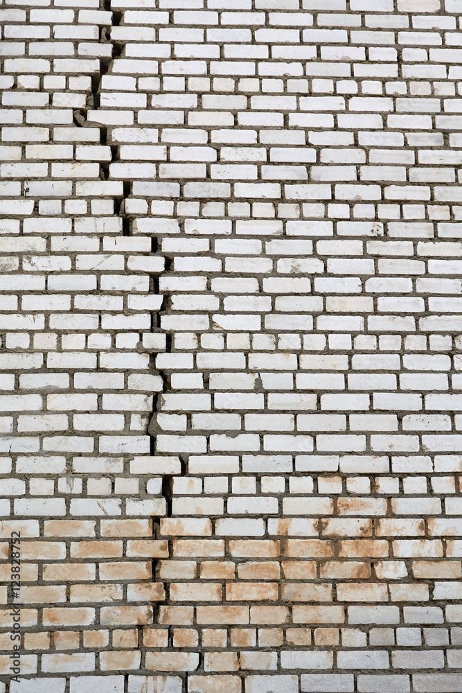 wall of white silicate bricks with a large vertical crack in the masonry