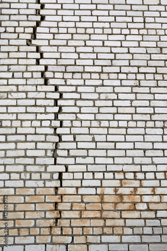 wall of white silicate bricks with a large vertical crack in the masonry