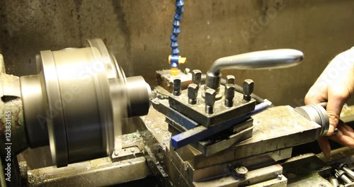 Technician working on lathe machine in workshop. Turner make part on the lathe.