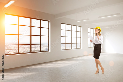 Woman in hardhat in empty room with windows