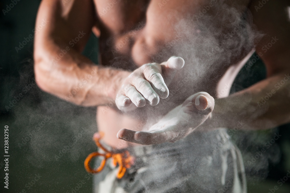 talc on bodybuilding athlete hands on background muscular physique in preparation for training in the gym