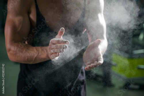 Photography talc on bodybuilding athlete hands on background muscular physique in preparatio