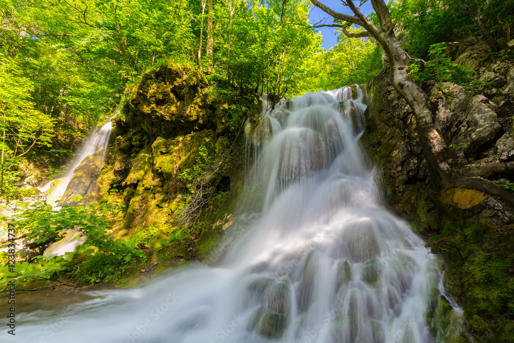 Naklejka premium Beautiful waterfalls in spring in the forest, on a bright sunny day