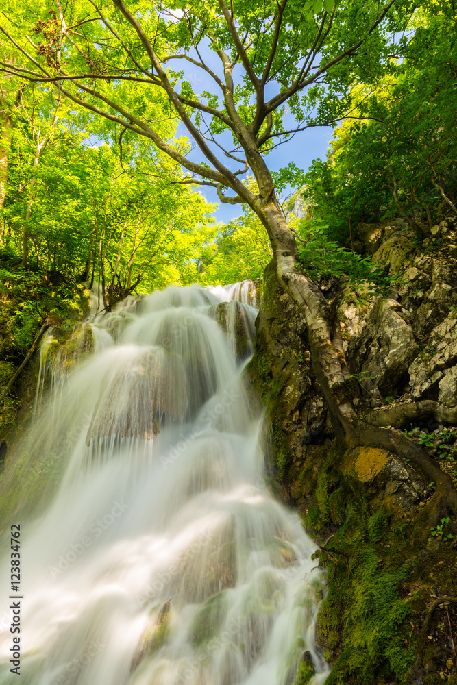 Beautiful waterfalls in spring in the forest, on a bright sunny day Beautiful waterfalls in spring in the forest, on a bright sunny day