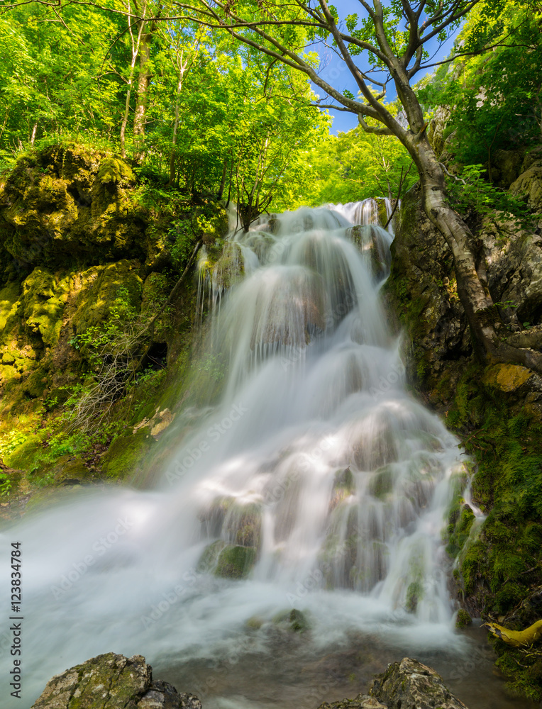 Pretty waterfalls deep in the woods, on a bright sunny day in spring