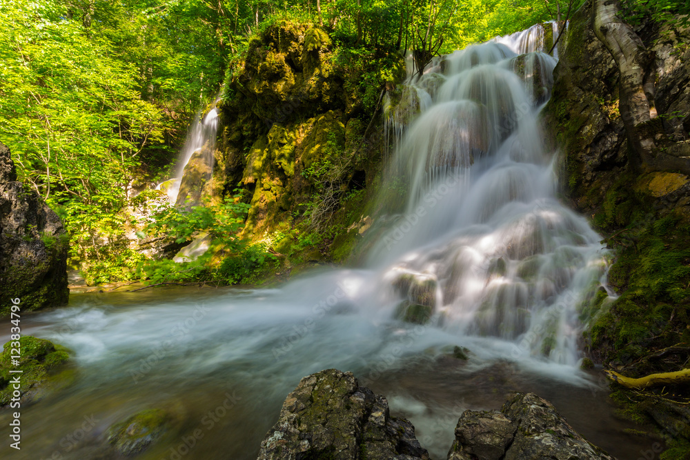 Pretty waterfalls deep in the woods, on a bright sunny day in spring Pretty waterfalls deep in the woods, on a bright sunny day in spring