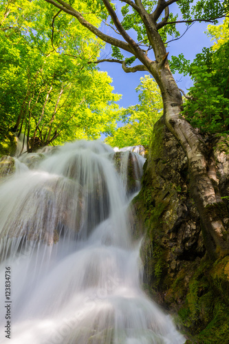 Beautiful waterfalls in spring in the forest, on a bright sunny day