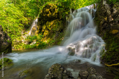 Fototapeta Naklejka Na Ścianę i Meble -  Pretty waterfalls deep in the woods, on a bright sunny day in spring