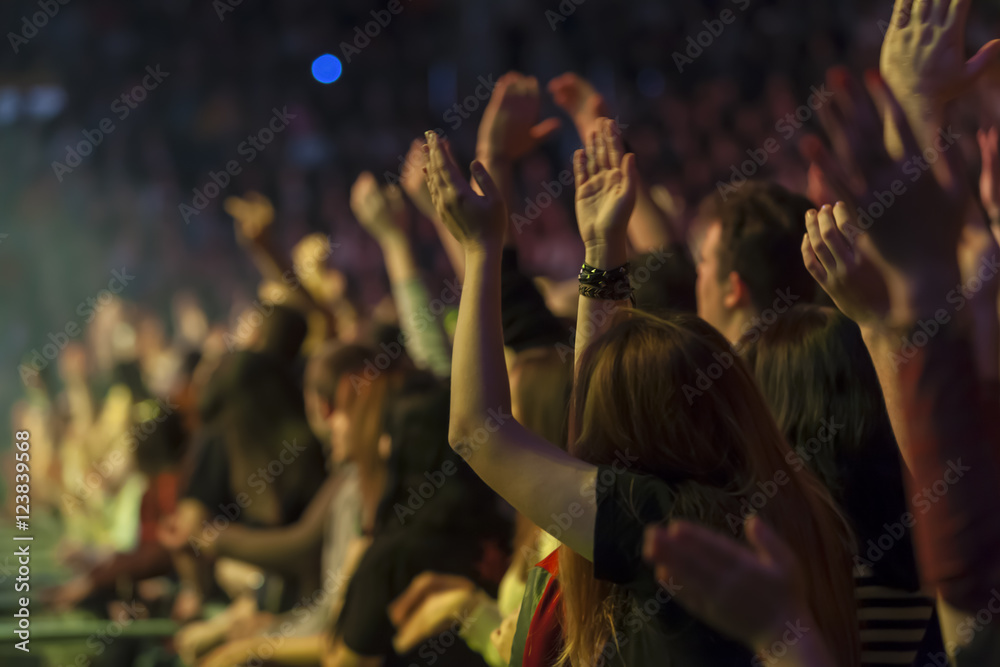 blurred image up raised hands of people at a concert in front of the stage