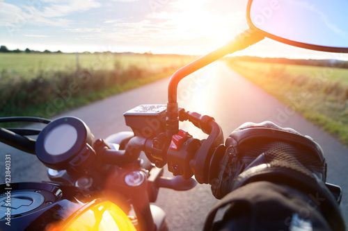 Motorrad fahren auf Landstrasse im Sonnenuntergang bei blauem Himmel photo