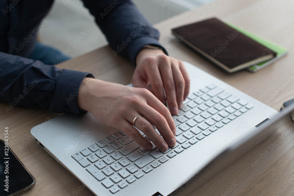 Hands typing on a laptop keyboard. A man works in an office at his workplace Hands typing on a laptop keyboard. A man works in an office at his workplace