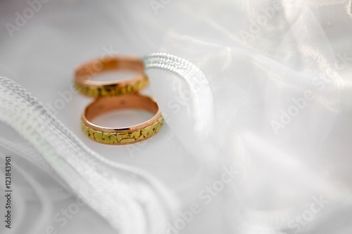 Engagement wedding rings. The ring of the bride and groom on a background of delicate white fabric wedding veils. Wedding accessories for the newlyweds.