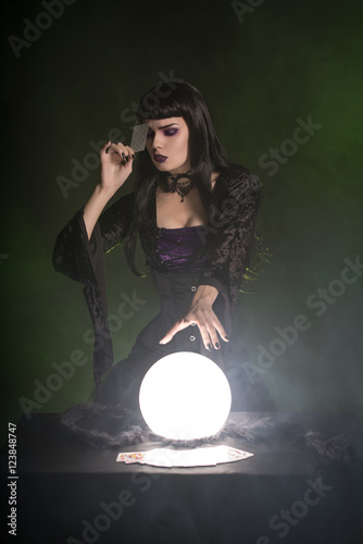 Attractive fortune teller with playing cards and crystal ball