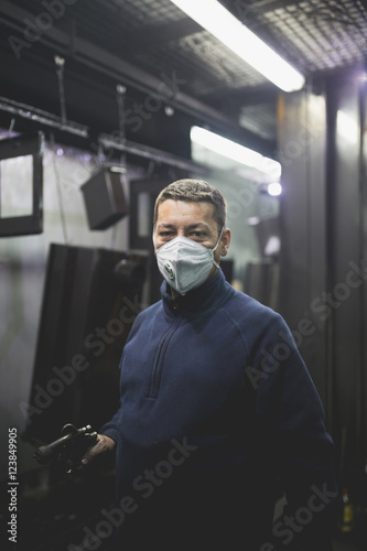Worker with protective mask in factory for production heavy pellet stoves and boilers.